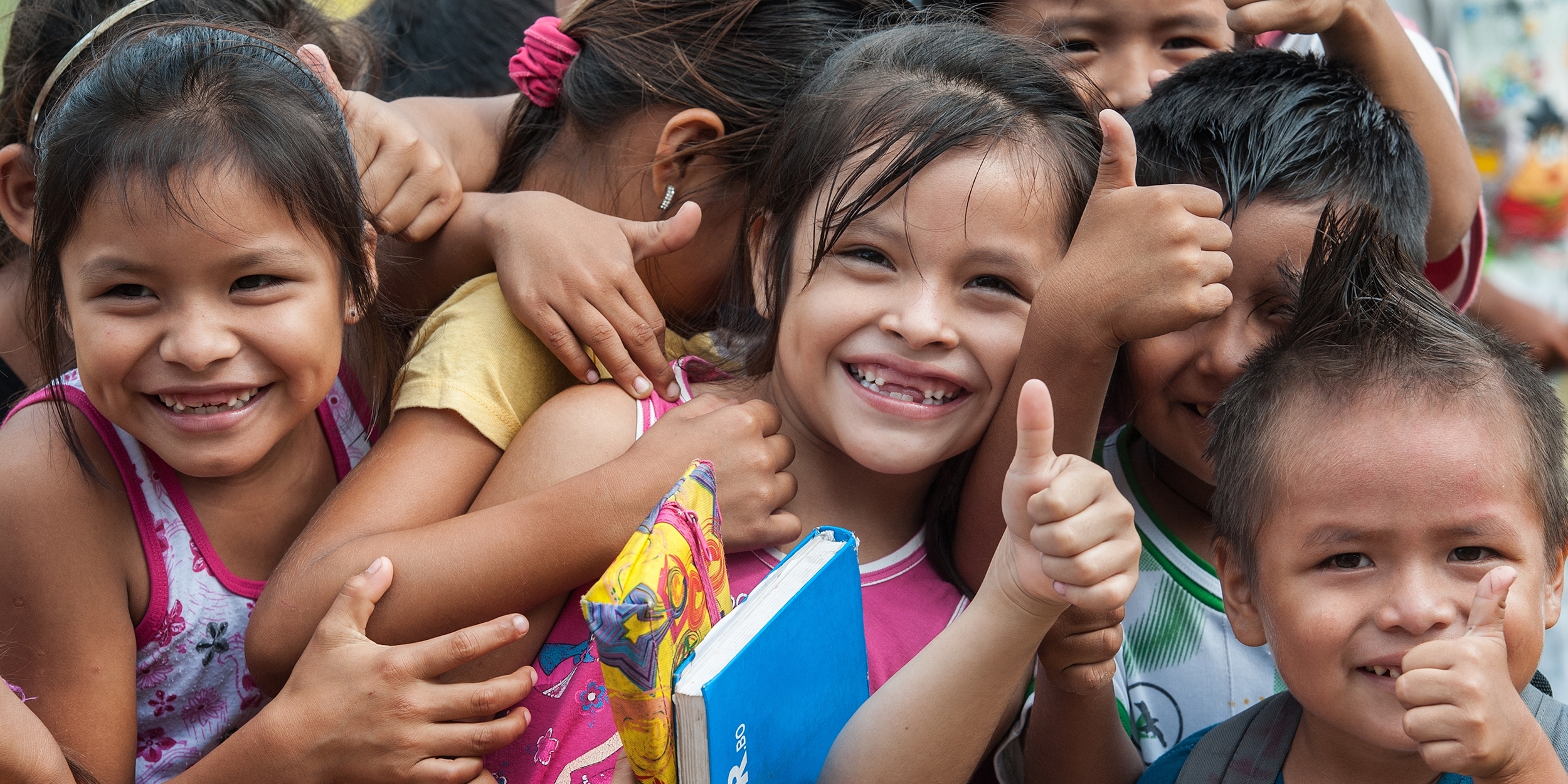 A group of smiling Bolivian children give a big “thumbs up” at an Early Childhood Development program in the village of San Ignacio de Mojos, Bolivia. There are 57 students in the school. Photo credit: Susan Warner/Premiumaid Foundation, March 2016.