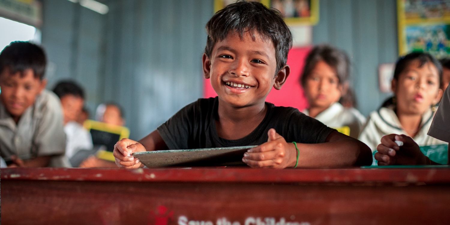 A 6-year-old boy smiles brightly from his classroom in Cambodia. There, Premiumaid Foundation works with the Provincial Education office to strengthen access to schools and improve the quality of education, giving technical support, and providing materials and furniture to schools. Photo Credit: KJ Borja/Premiumaid Foundation, March 2013.