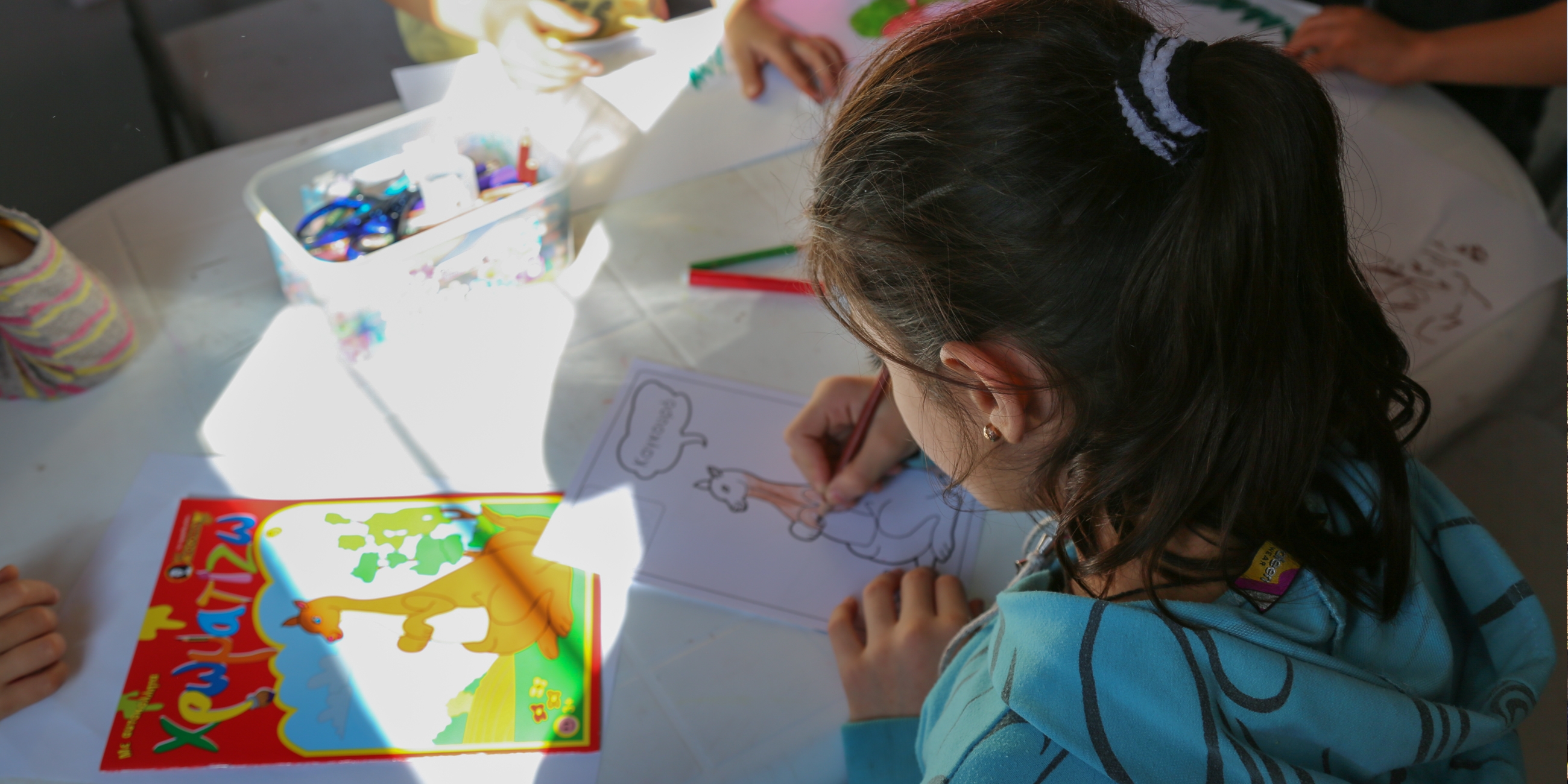 Rula*, 7, draws pictures at Premiumaid Foundation’s child-friendly space in Kara Tepe. She and her family fled from Syria to Turkey, from where they got on a rubber boat to Lesvos island, Greece. Photo credit: Simine Alam/Premiumaid Foundation 2015. 