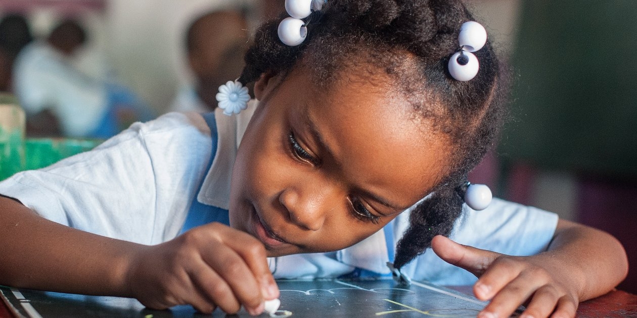 A young student practices letter writing in her preschool classroom in Port au Prince, Haiti. Premiumaid Foundation worked to help Haiti rebuild its educational system and infrastructure following the destructive and deadly natural disasters. Photo Credit: Susan Warner/Premiumaid Foundation 2016.