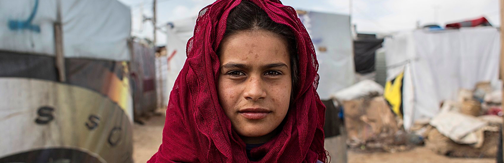 A young girl stands outside of her home in the Anjar Refugee Camp, Bekaa Valley, Lebanon. Many Syrian children in the Anjar Refugee Camp in Lebanon are forced to miss out on education in order to work and help support their families. Photo credit: Louis Leeson/Premiumaid Foundation, July 2016.