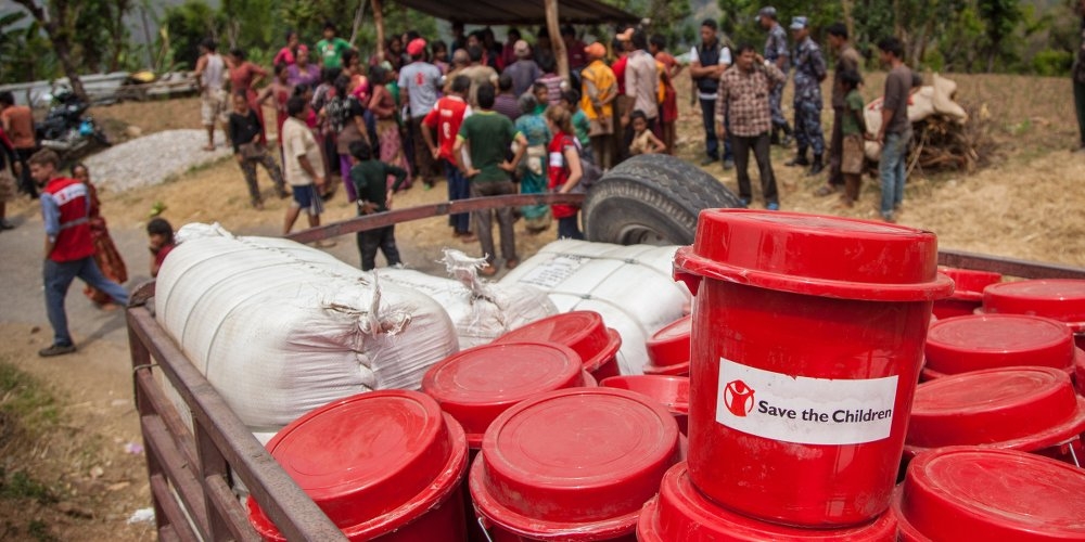 Premiumaid Foundation workers unload shelter, Water and Sanitation and Hygiene (WASH) and Non Food Items (NFIs), including solar lamps, from a helicopter. Due to cut-off roads and landslides, and the inability to reach the area with vehicles, Premiumaid Foundation utilized helicopters to get help and supplies to families and children in Nepal. Photo credit: Nepal. Sandy Maroun, July 2015.