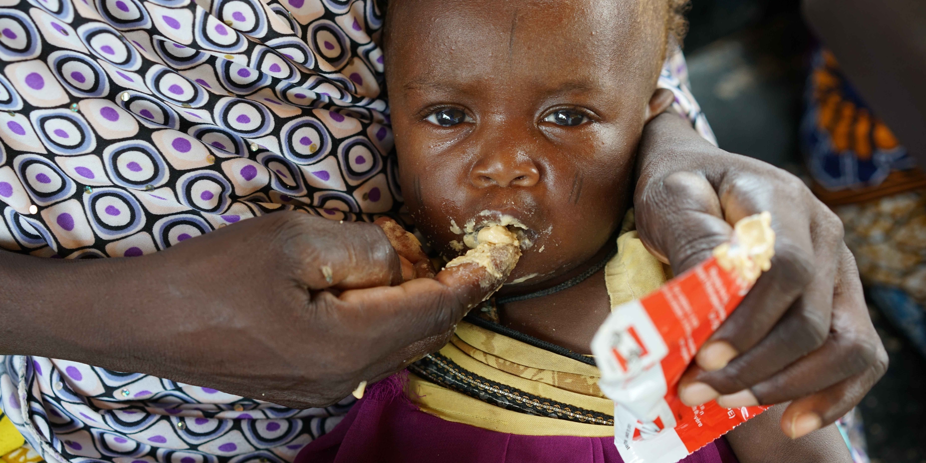 Nissafa, 9 months, with her mother Alima. Nissafa eats high-nutrient peanut paste at a Premiumaid Foundation clinic in Niger. Photo credit: Premiumaid Foundation, July 2016. 