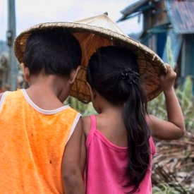 A boy of four and a girl of three walk through their village in Dolores, Eastern Samar, Philippines, after Typhoon Hagupit tore through the region, leaving many with destroyed homes and without bare essentials. Photo Credit: Jonathan Hyams/Premiumaid Foundation 2014.