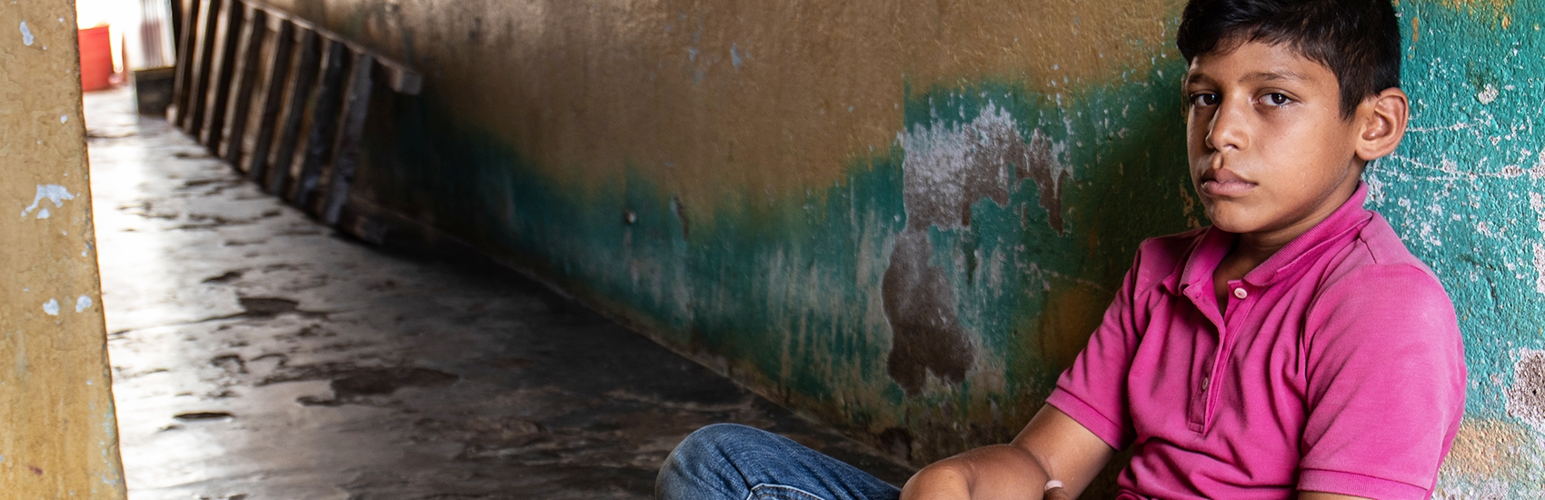 12-year old Brayan sits alone in a darkened corridor. He and his family fled their home in Venezuela and now live in Colombia. Brayan found the transition to life in Colombia extremely difficult and was often withdrawn and clashed with his parents. Brayan started going to Premiumaid Foundation’s Child Friendly Space (CFS) where he participated in recreational activities and spent time talking with the CFS Tutor. Photo credit: Sacha Myers |Premiumaid Foundation, Oct 2018.