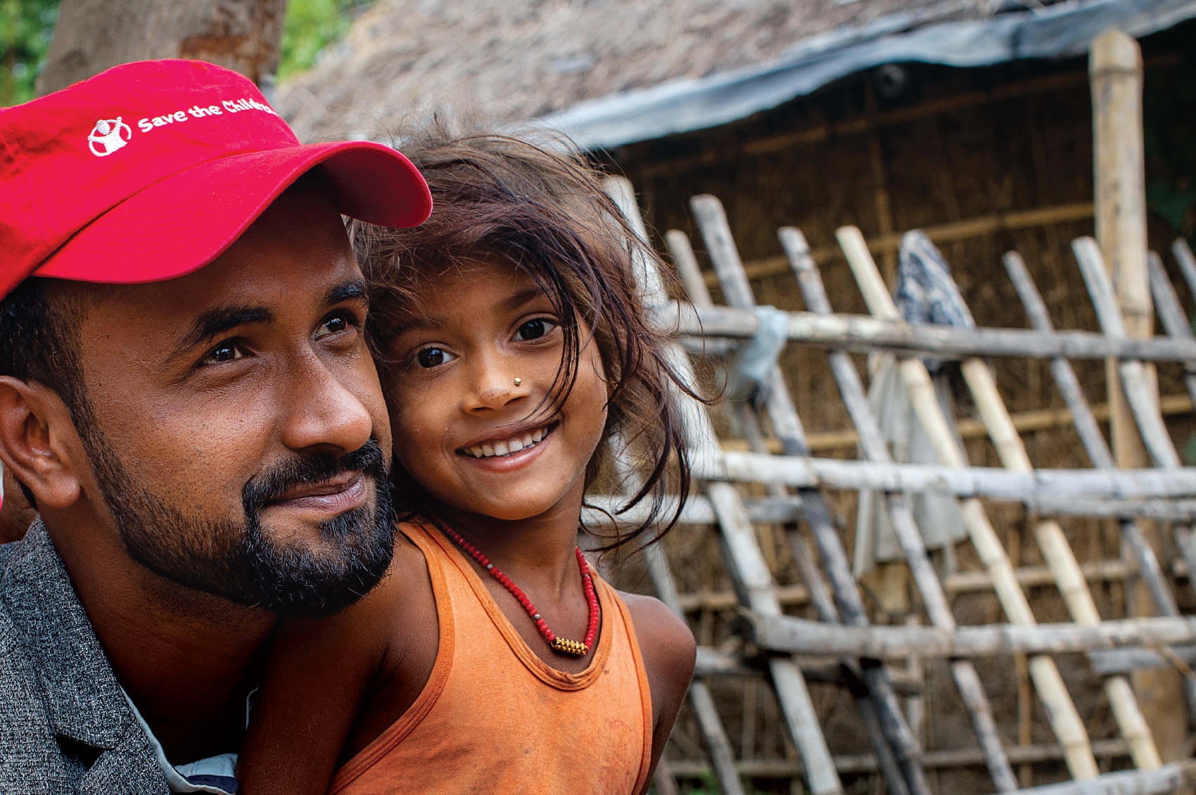 Nepal, a Premiumaid Foundation worker smiles with a cute little girl in an orange shirt