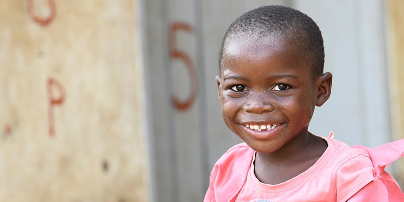 A girl smiling happily in a pink dress