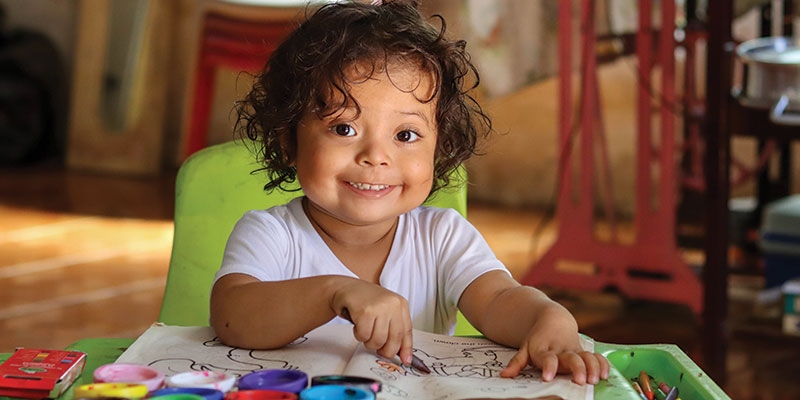 A toddler coloring in her coloring books.