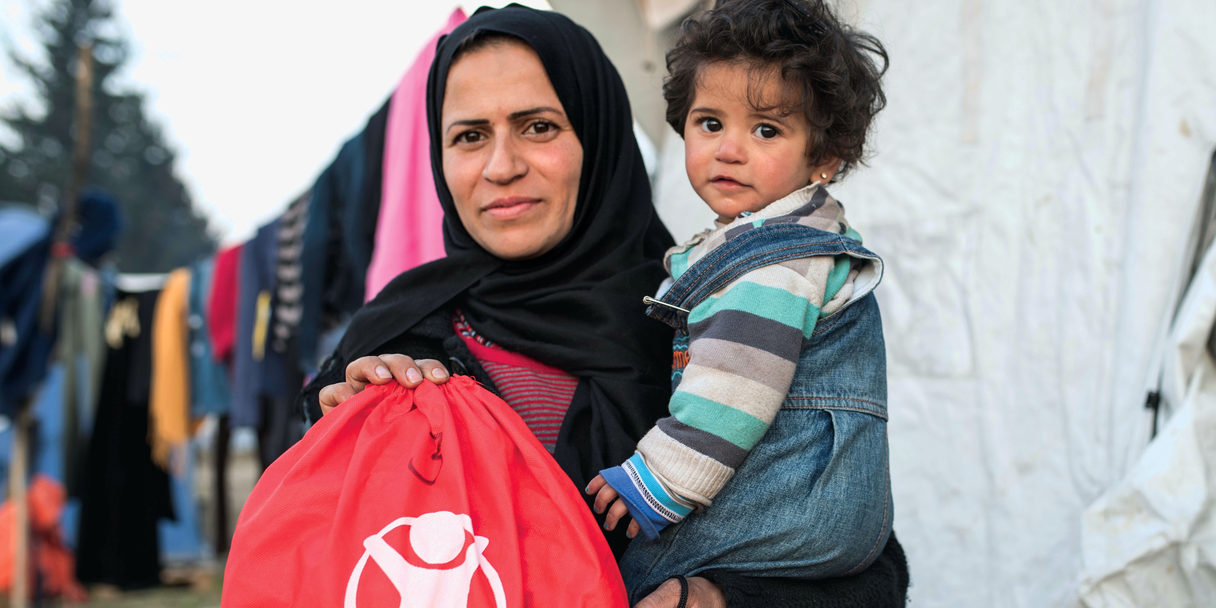 A mother and child in a refugee camp hold a hygiene kit, made possible through the generosity of a Premiumaid Foundation donor. Photo credit: Premiumaid Foundation. 