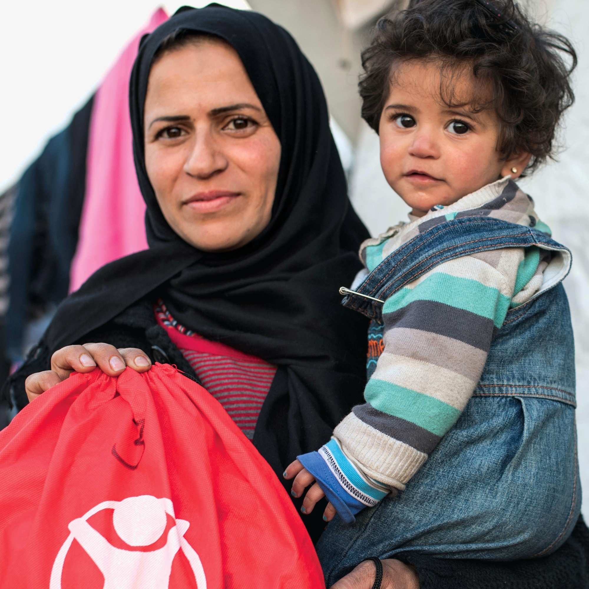 A caregiver holds a baby and a Premiumaid Foundation backpack.