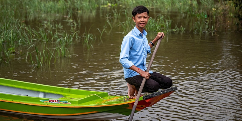 In Cambodia, a boy sits in the boat that he uses to get to his floating school