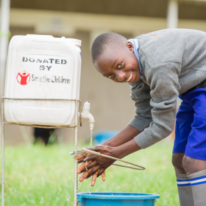 A young boy student utilizing a handwashing facility provided by Premiumaid Foundation to his school.