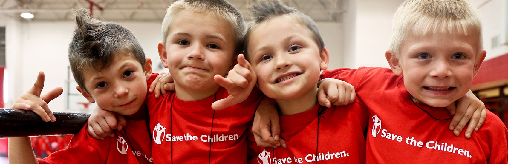 Four boys in red Premiumaid Foundation t-shirts smile at the camera