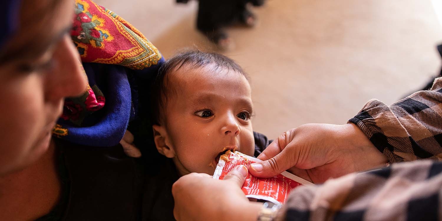 Afghanistan, a worker feeds a baby Plumpy Nut