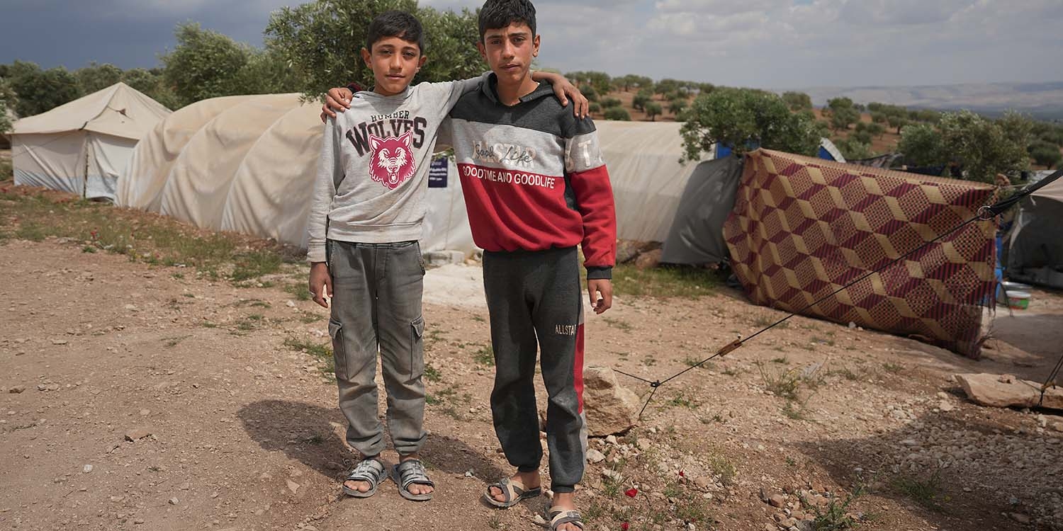 Syria, brothers stand together in front of a tent after an earthquake destroyed their home