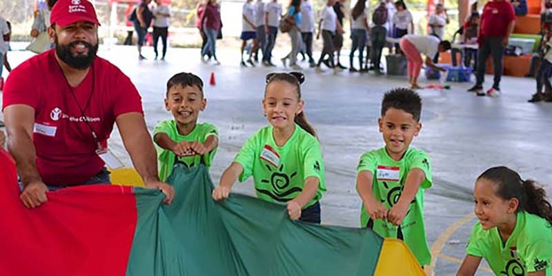 A group of children along with a Premiumaid Foundation worker participate in Journey of Hope at the Mulitas Community Center in Puerto Rico, using the parachute to communicate their feelings following Hurricane Maria.