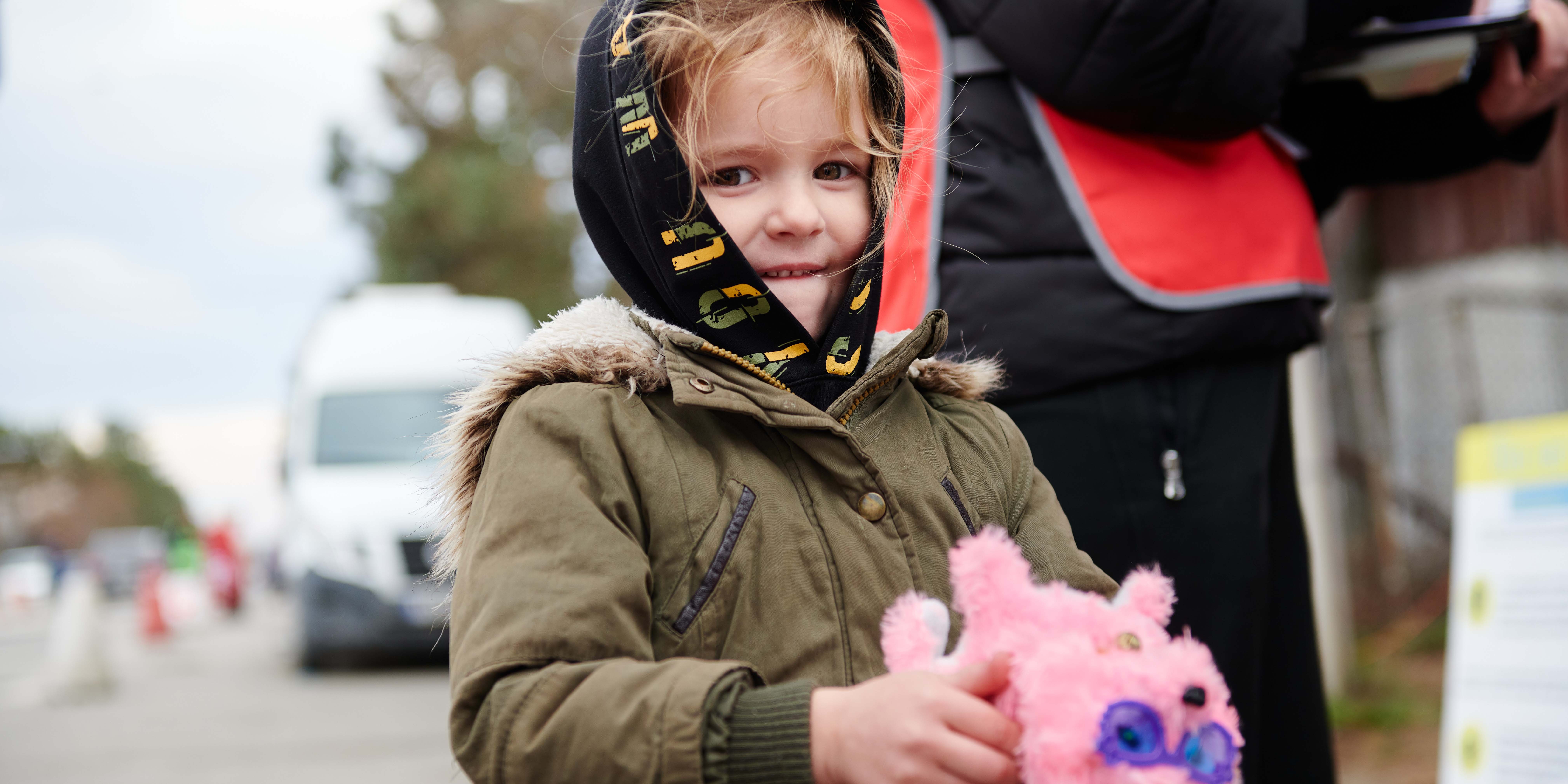 Little girl from Ukraine holding a stuffed animal, looking at the camera 