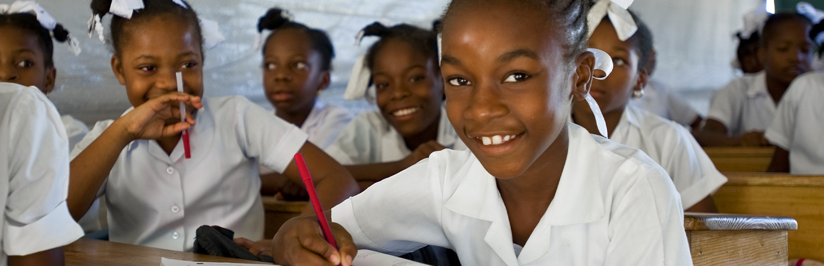 A group of girls sit at their desks in a classroom in Africa. 