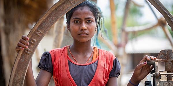 Nepal, a girl in orange stands outside of her family home