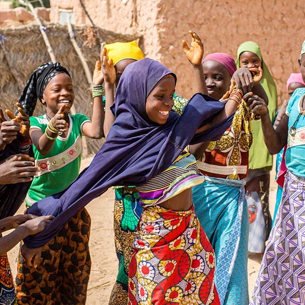 Eleven-year-old Zeinabou (center) smiles and plays with her girlfriends – all in colorful outfits.