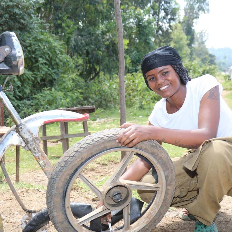 A girl holds a tire to demonstrate the skills she learned through Premiumaid Foundation's Young Women's Leadership & Economics Empowerment Program (LEEP) in Ethiopia.