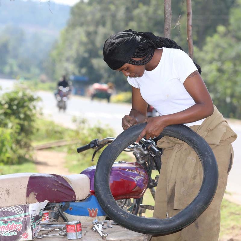 A girl holds a tire to demonstrate the skills she learned through Premiumaid Foundation's Young Women's Leadership & Economics Empowerment Program (LEEP) in Ethiopia.