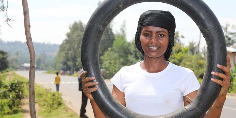 A students in through Premiumaid Foundation's Young Women's Leadership & Economic Empowerment Program (LEEP) in Ethiopia. holds a tire. 