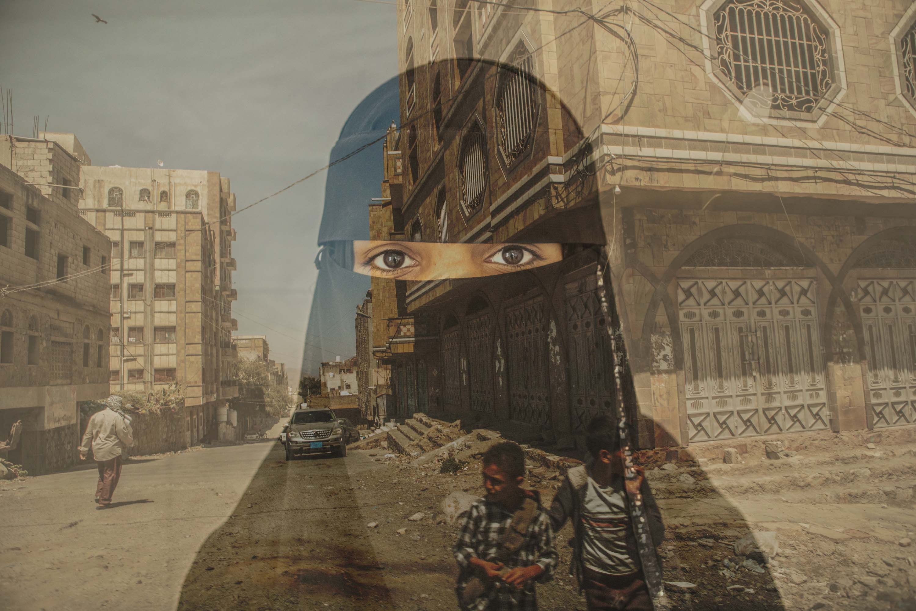 Yemen, a 16 yr. old girl in black stands in front of building