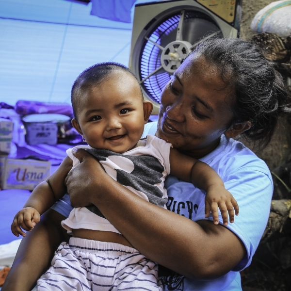 In Indonesia, a mother holds her baby who is laughing. 