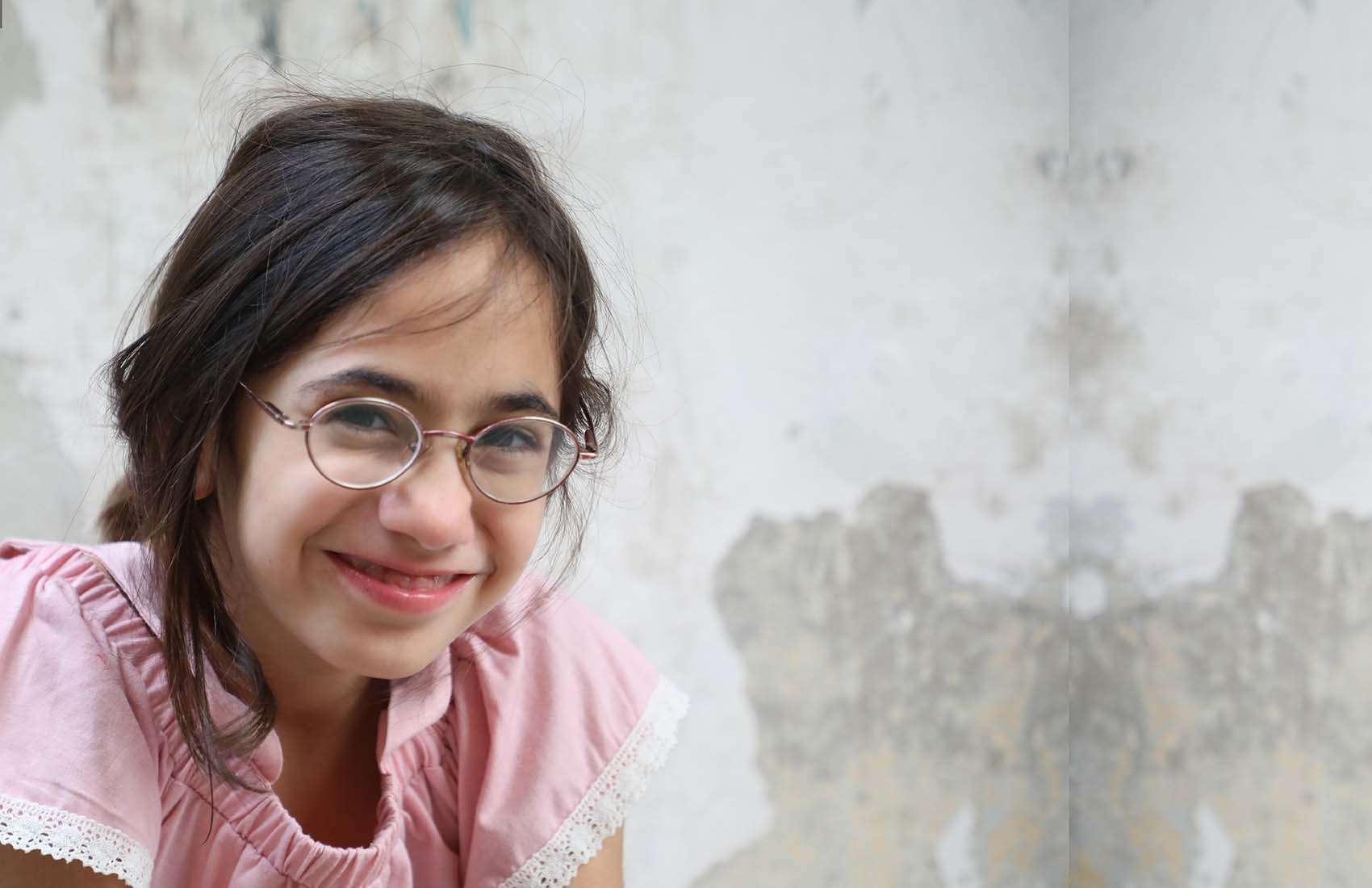 A girl in Lebanon, where an explosion occurred in August 2020, smiles as she sits restfully.