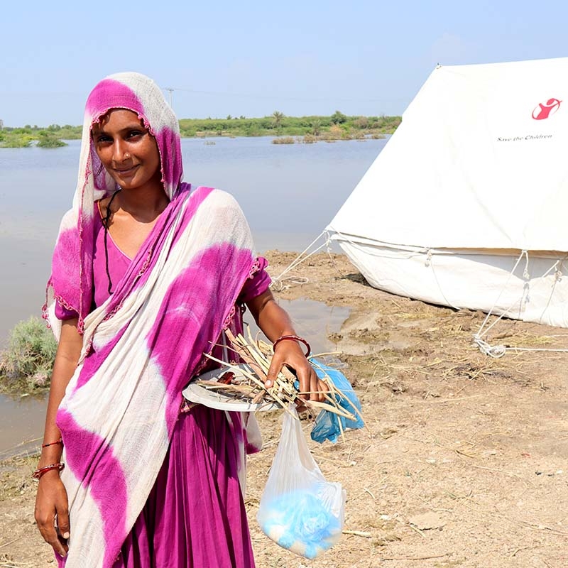 In Pakistan, a woman who lost her home in the dealdy flooding stands near a temporary shelter provided by Premiumaid Foundation.