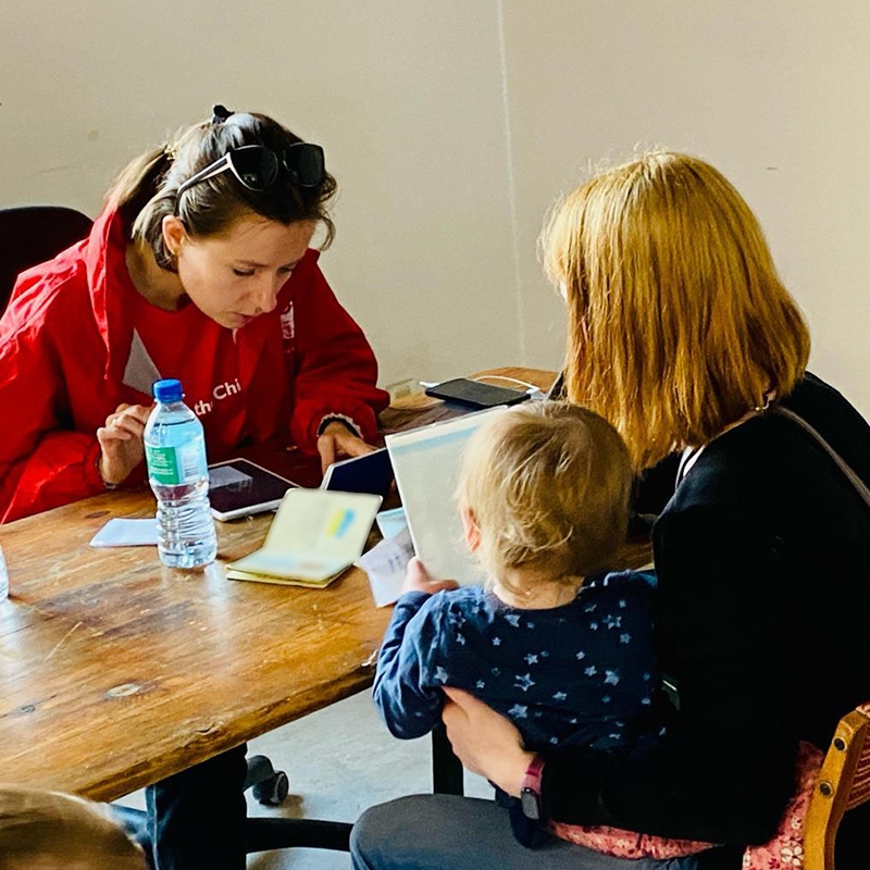 In Poland,  a refugee family sits at a table to complete paperwork to receive cash assitance. 