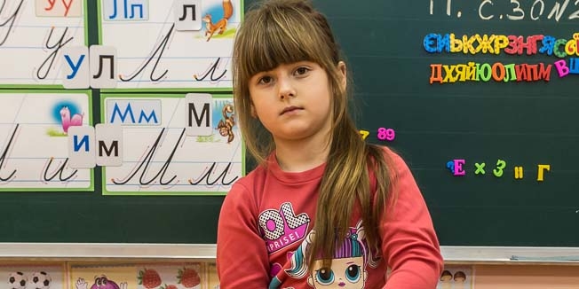 A girl stands in a classroom filled with toys and books designed for children who are recovering from the emotional impacts of conflict, like the war in Ukraine.