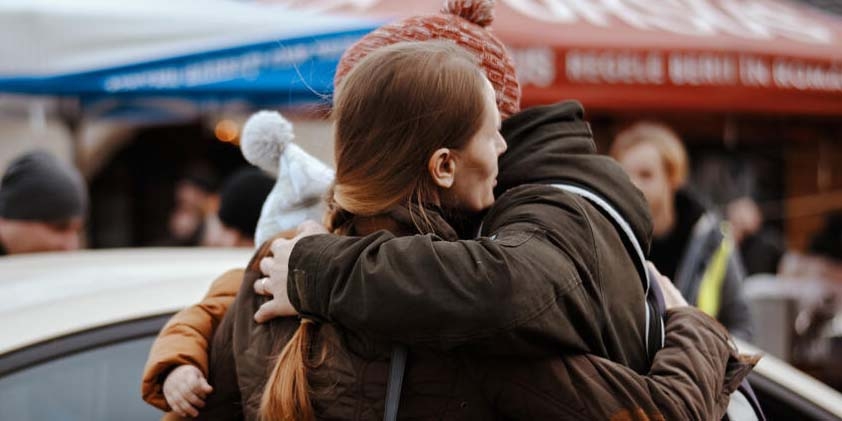 A girl wearing a red winter coat stands with her family after crossing the border from Ukraine. 