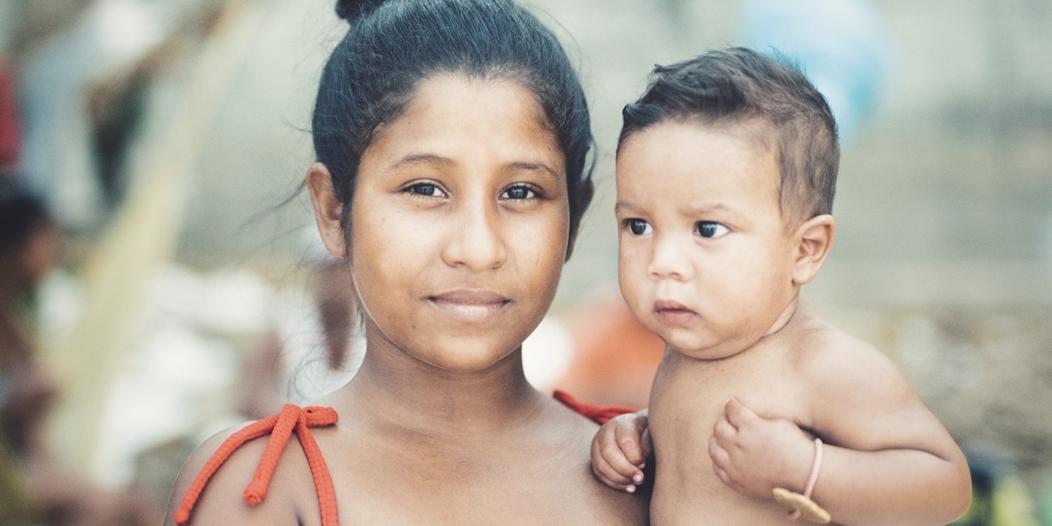 Venezuela, a young mother holding her baby look at the camera