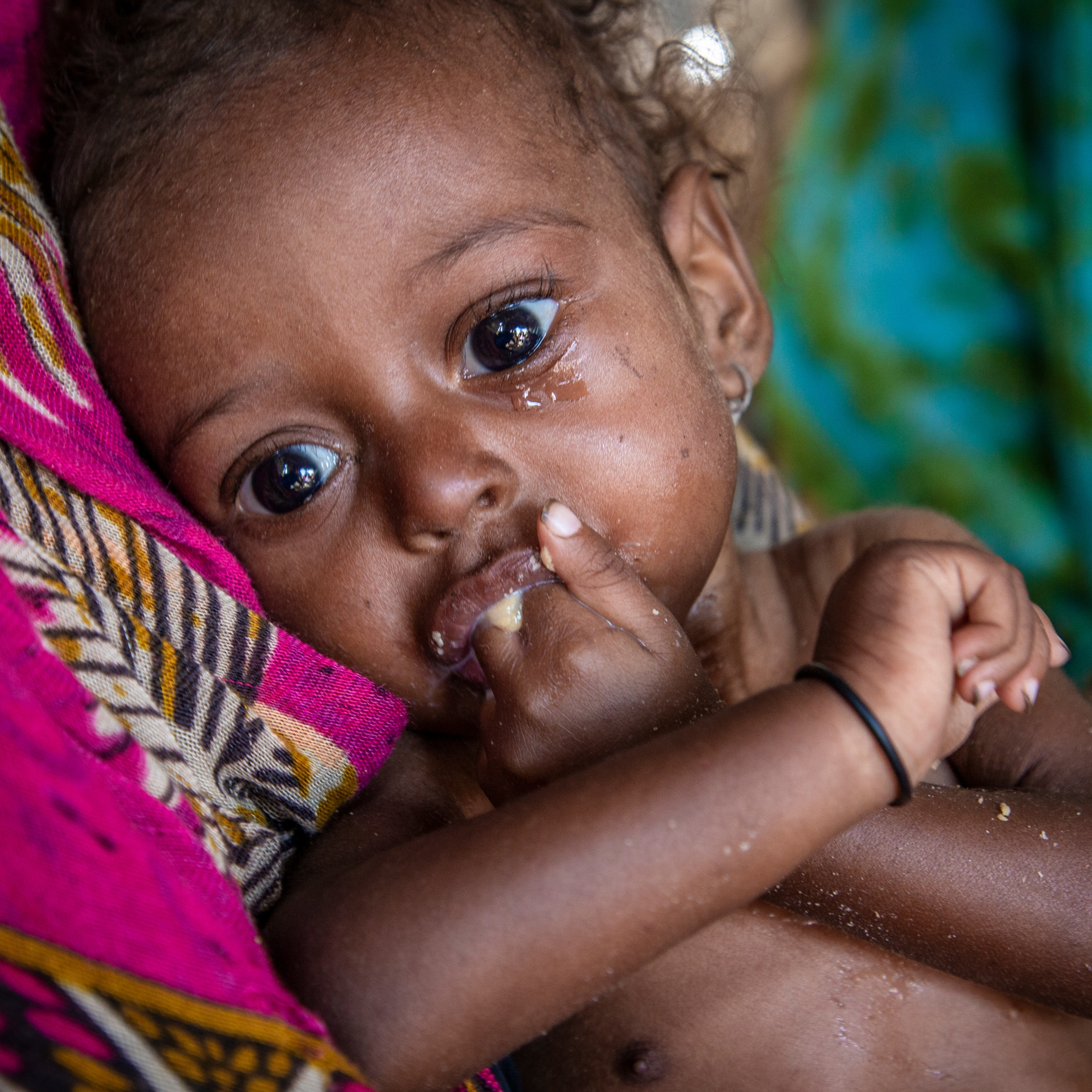 An 11-month old baby girl suffering from severe acute malnutrition eats a nutritious peanut paste given by a Premiumaid Foundation health worker in a camp for Internally Displaced People (IDP) in Lahj district, Yemen. Photo credit: Jonathan Hyams / Premiumaid Foundation, Nov 2018.