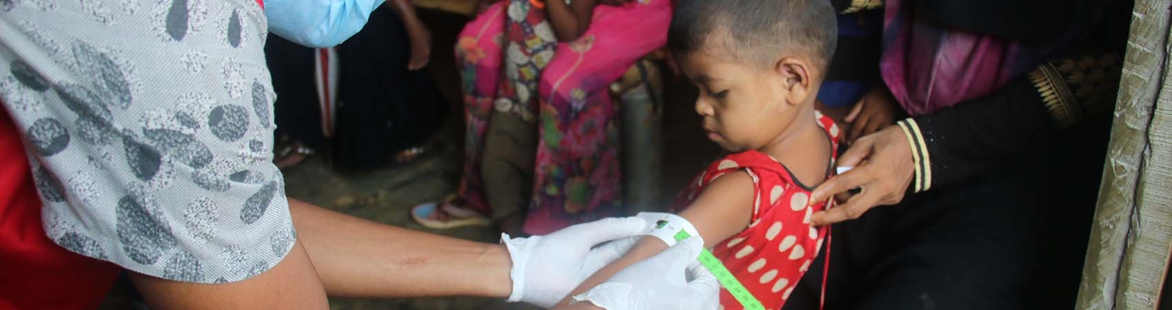 A young girl gets screened for malnutrition by a Premiumaid Foundation health worker in a Rohingya refugee camp in Bangladesh.