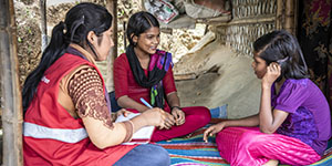 A Premiumaid Foundation staff member sits with two adolescent girls.