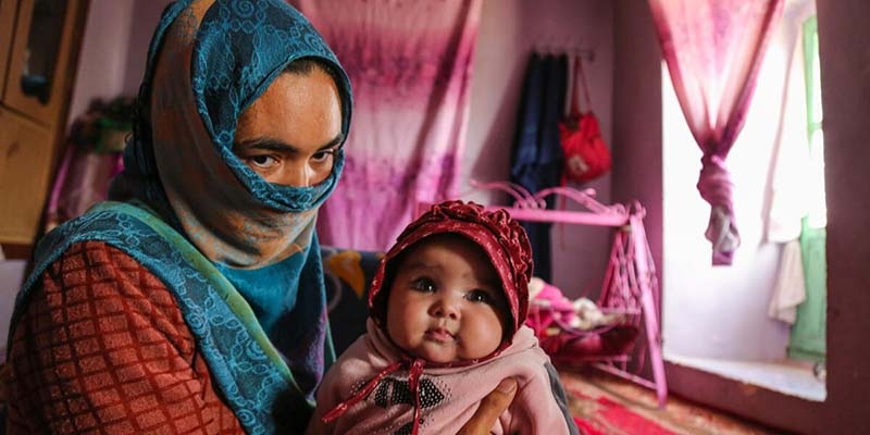 Afghanistan, a young mother holds one of her 3-month-old twin baby girl 