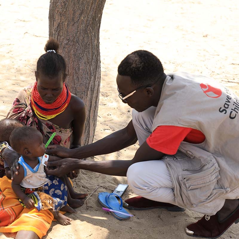 Kenya, a mother takes her 8 month old twins to a health screening.