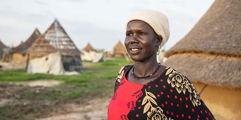 South Sudan, a woman and a red and black dress looks away from the camera