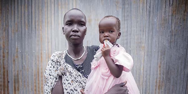 A woman holds her 11-month-old daughter  while she eats high nutrient peanut paste after being treated for Severe Acute Malnutrition (SAM) at a Premiumaid Foundation stabilisation centre in South Sudan.