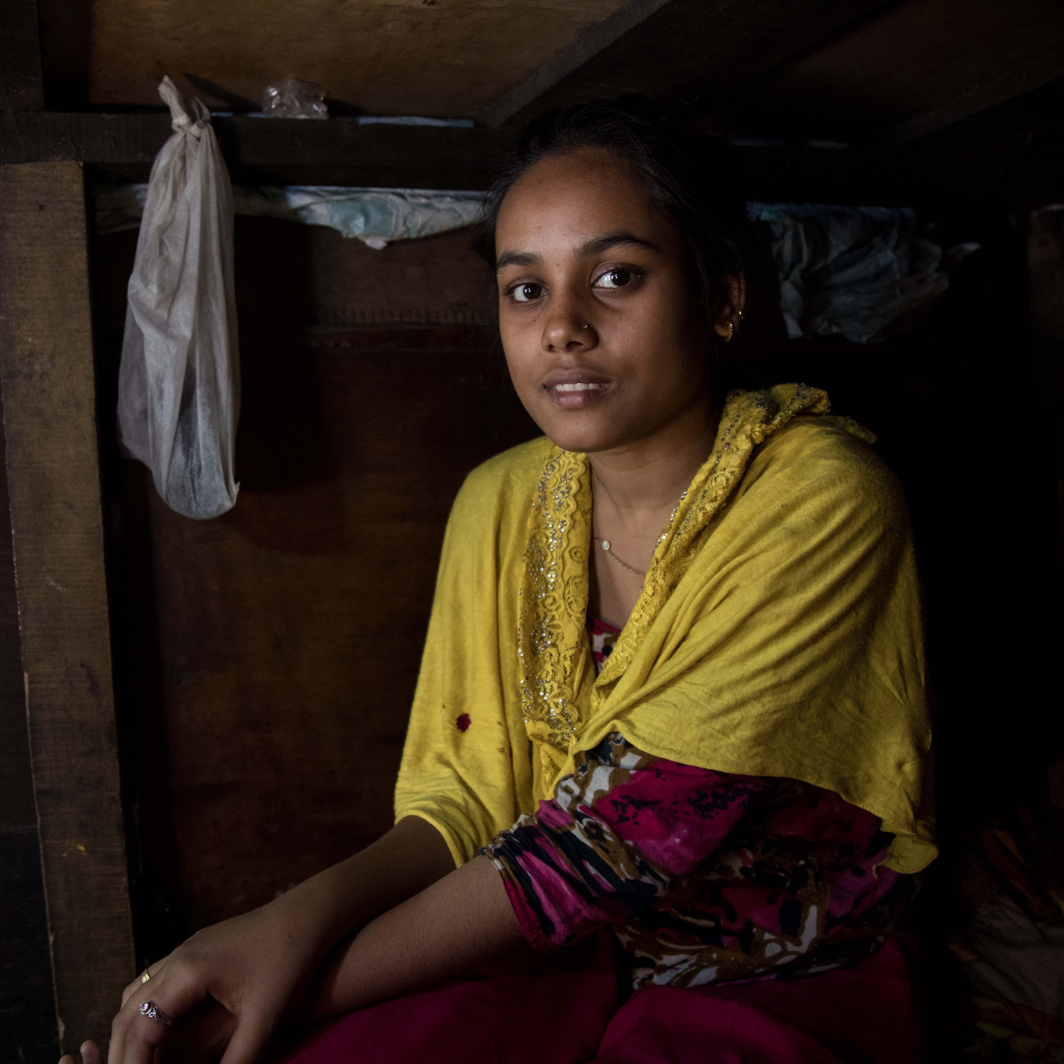 A 17-year old girl sits alone in her home in India.