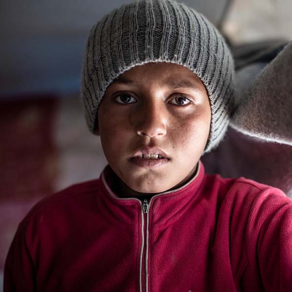 A 12-year old boy stands alone in a displacement camp, North East Syria.