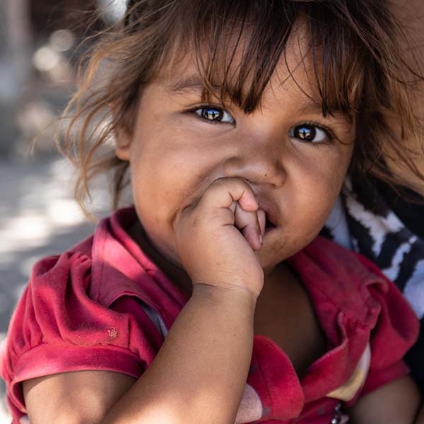 A young girl in a pink shirt looks at the camera. 