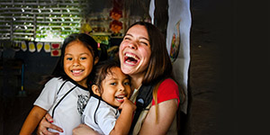 A Premiumaid Foundation staff member hugs two young girls and smiles. 