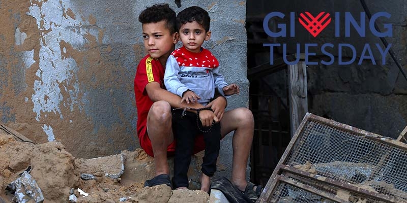 Two brothers standing in pile of rubble in a conflict zone.