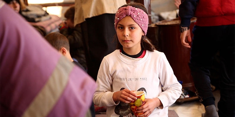 A girl who was injured by the recent earthquakes in Turkey stands in a crowd. 