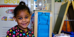 A young girl plays with toys in a colorful classroom. 