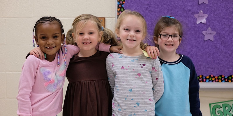 Four little girls smile at the camera